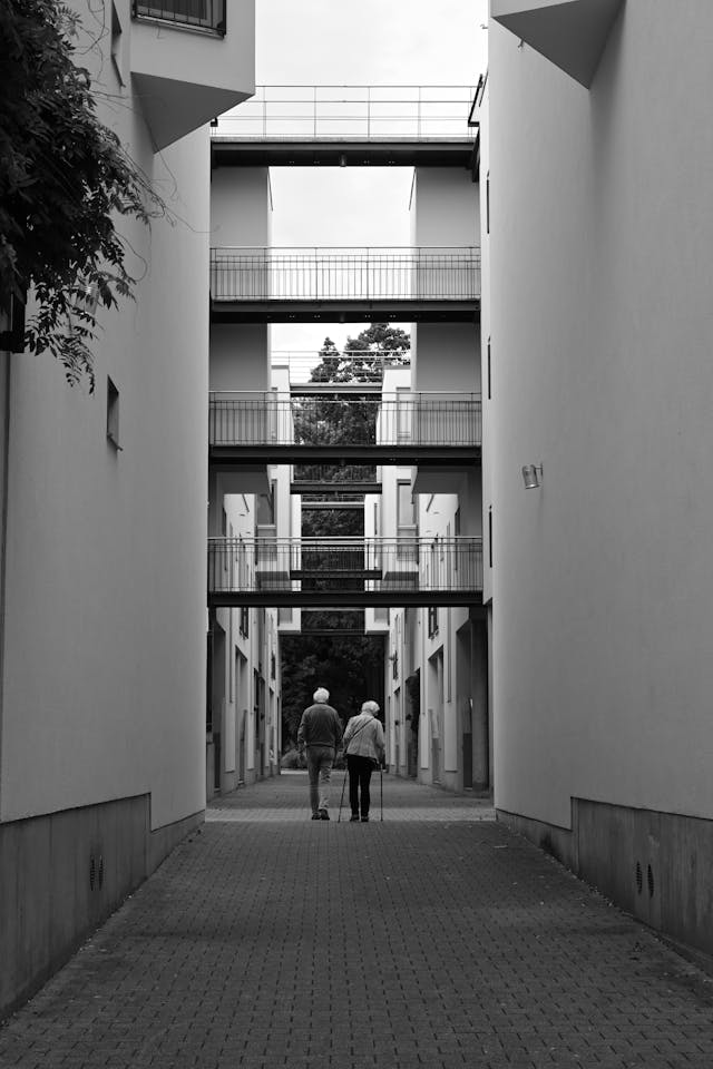 Old people waling away from camera in apartment complex